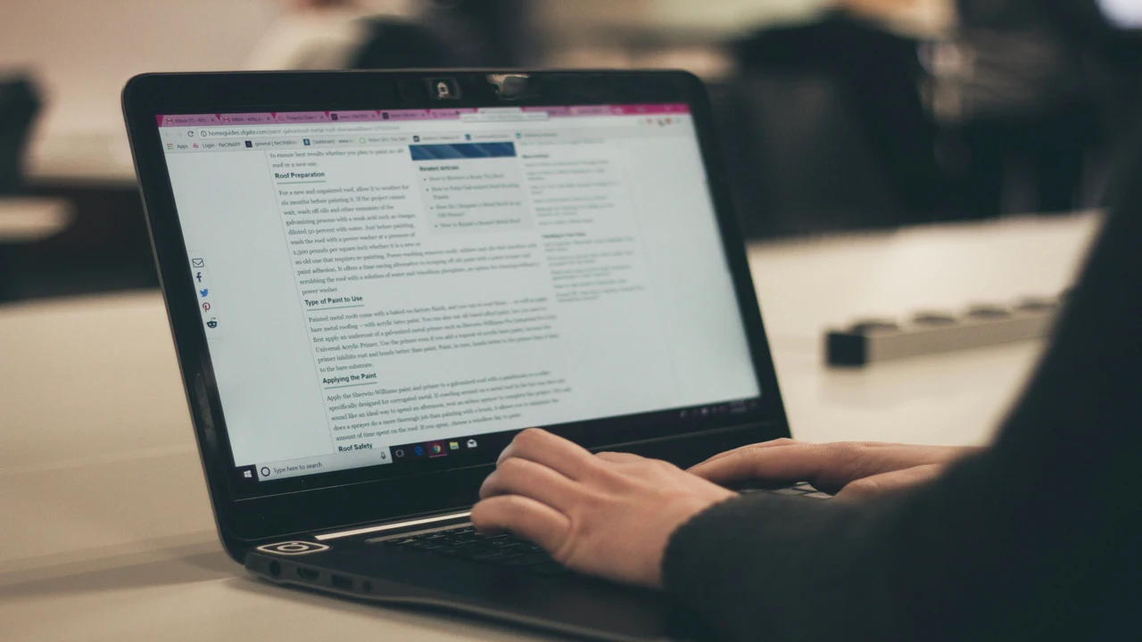 Person typing in a laptop placed on a table.